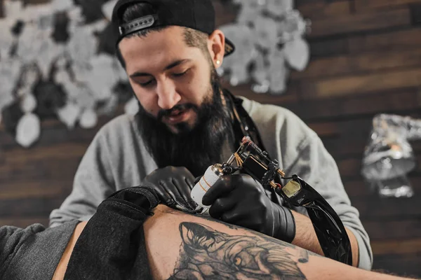 Tattoo master is tattooing in the tattoosalon — Stock Photo, Image