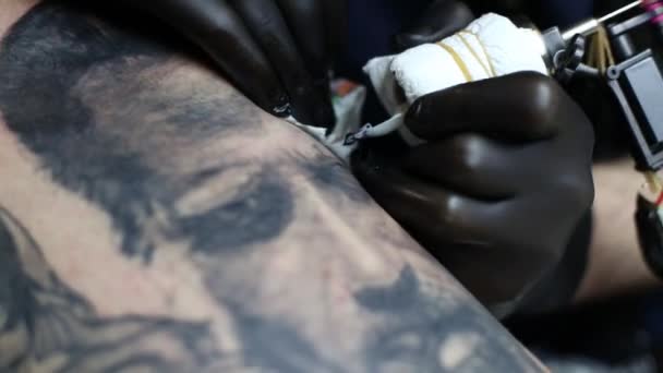 Maître de tatouage en gants noirs, tatouage sur la peau 