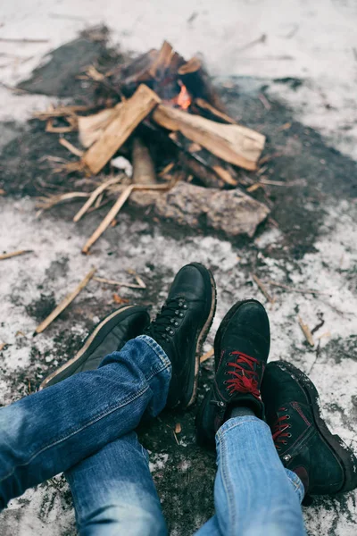 Guy and girl warm feet near a fire