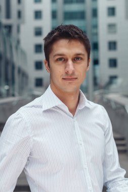 Bir kent meydanında ayakta gülümseyen rahat iş adamı