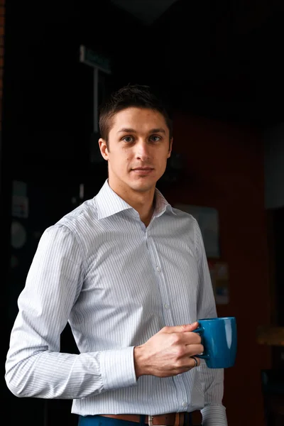 Coffee break. Confident young handsome man in blue pants