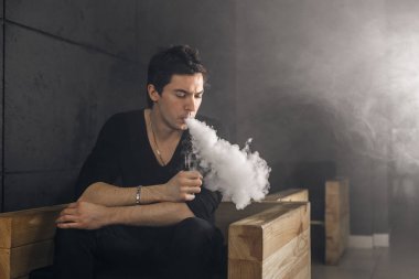 Mod tutan bir buharlı adam. Bir buhar bulutu. Siyah arkaplan.