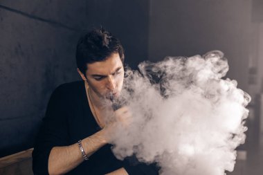 Mod tutan bir buharlı adam. Bir buhar bulutu. Siyah arkaplan.