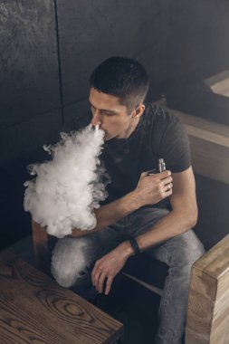 Mod tutan bir buharlı adam. Bir buhar bulutu. Siyah arkaplan.