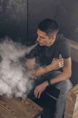 Mod tutan bir buharlı adam. Bir buhar bulutu. Siyah arkaplan.