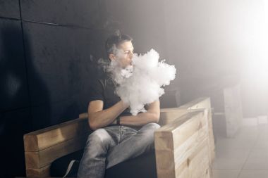 Mod tutan bir buharlı adam. Bir buhar bulutu. Siyah arkaplan.