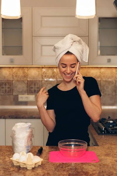 Mujer hablando por teléfono celular y cocinando en la cocina con alegría — Foto de Stock