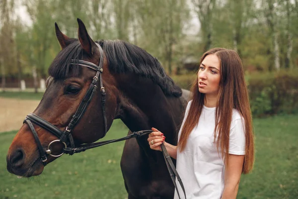 Vacker flicka kommunicerar med en häst i parken — Stockfoto