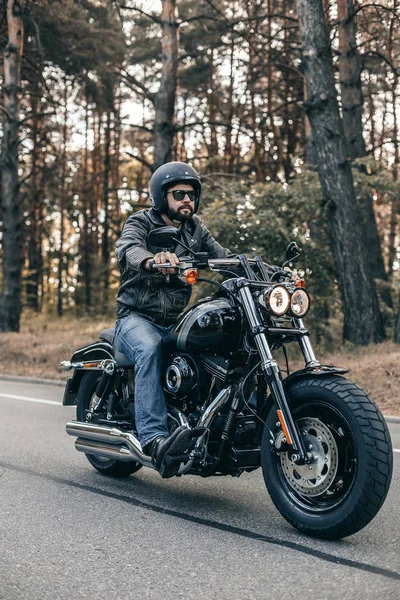 Чоловік сидить на мотоциклі на лісовій дорозі під час сходу сонця — стокове фото