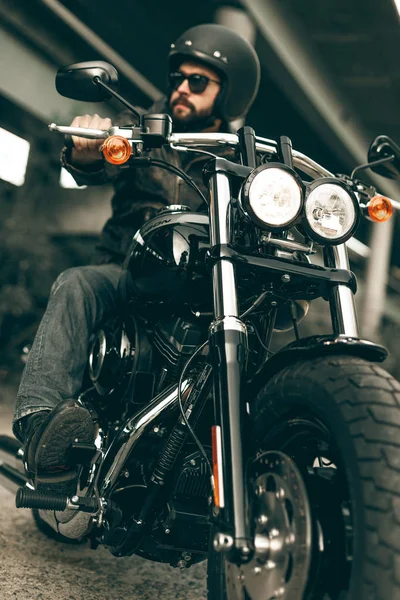 Байкер в шлеме и его стиль мотоцикл на улицах города — стоковое фото