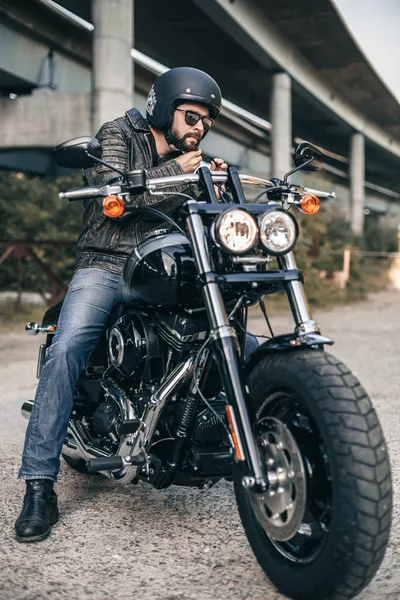 Молодой жестокий человек в черной куртке и очках на мотоцикле — стоковое фото