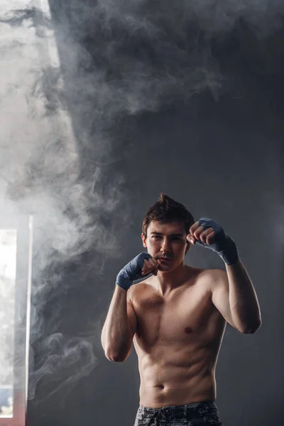 Jóképű férfi a fénysugarak a nap és a füst boksz edzőterem — Stock Fotó