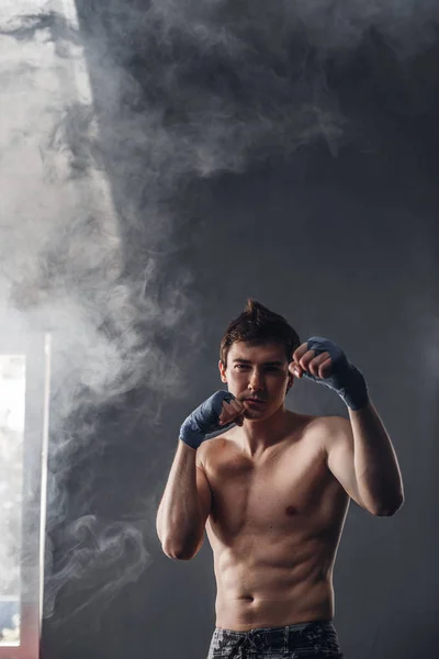 Bonito homem nos raios do sol e fumaça boxe no ginásio — Fotografia de Stock