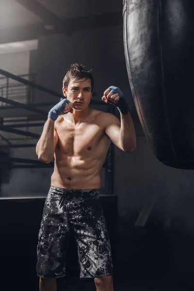 Bir kum torbası ile boks egzersiz adlı genç sporcu — Stok fotoğraf