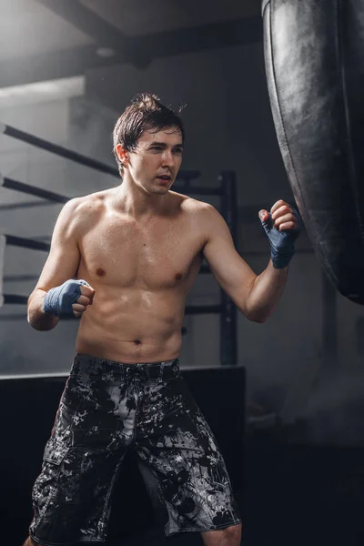 Homem praticando boxe em grande saco preto no ginásio — Fotografia de Stock