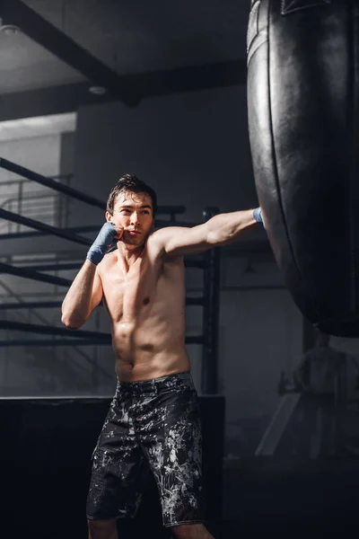 Boxeo masculino en saco de boxeo en un gimnasio deportivo —  Fotos de Stock