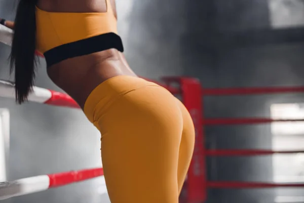 Сексуальная красивая спортивная задница, женщина на боксерском ринге, опирающаяся на веревку — стоковое фото
