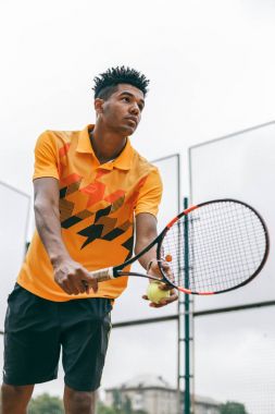 Raket tenis topu hizmet vermeye hazır olan genç tenisçi.