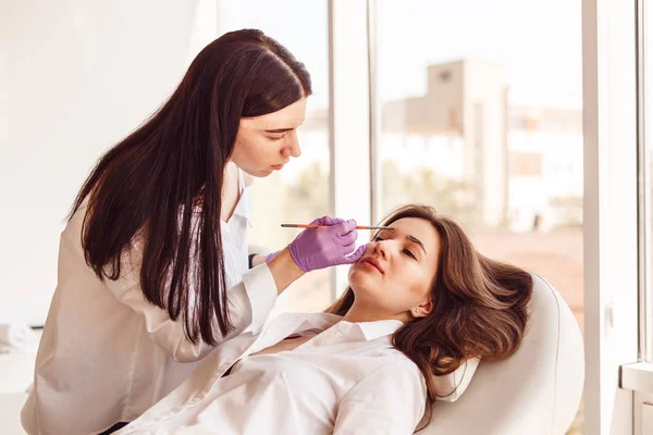 Cliente femenino está acostado en un sofá blanco durante la corrección y el estilo de cejas . — Foto de Stock