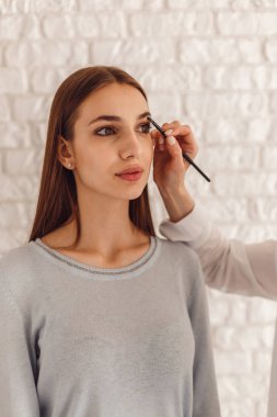 Güzel kadın ve kozmetik fırça kullanarak kaşları bir şeklin çizim güzellik uzmanı