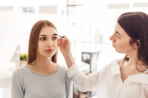 Master makeup korrigerar och ger formen för ögonbryn i en skönhetssalong. — Stockfoto