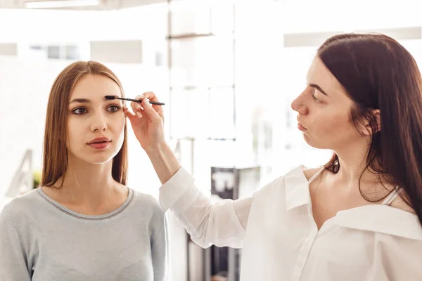 Master makeup korrigerar och ger formen för ögonbryn i en skönhetssalong. — Stockfoto