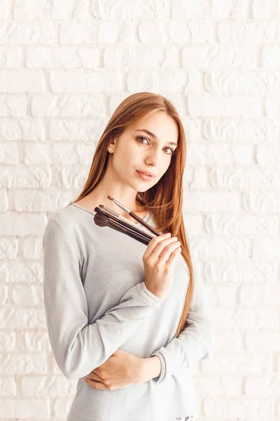 Vacker ung kvinna med naken ansikte makeup med borstar för makeup — Stockfoto