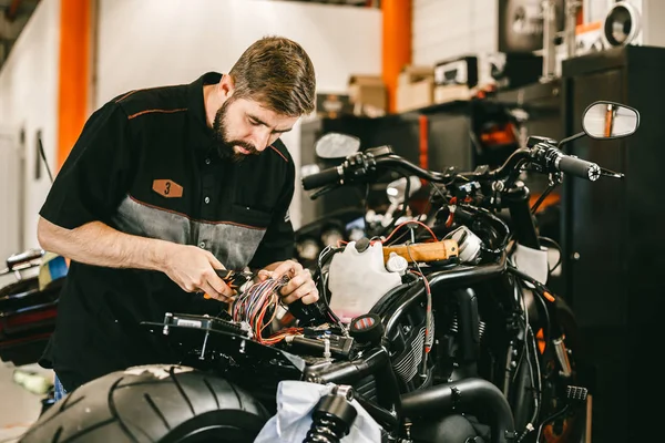 Professioneller Motorradmechaniker arbeitet mit Elektronik, schneidet Drähte. — Stockfoto