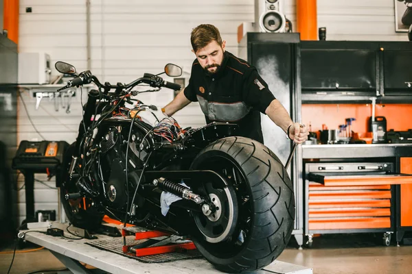 Mechaniker wechselt Motorradrad in Fahrradwerkstatt. — Stockfoto