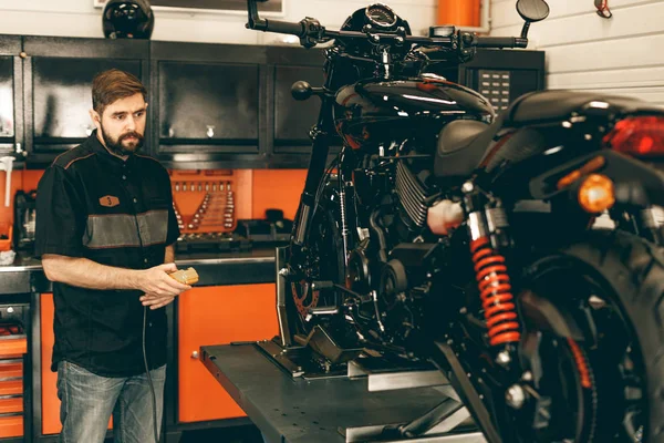 Berufsmotormechaniker hebt ein Motorrad auf die Hebebühne. — Stockfoto