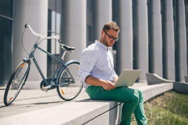Genç adam şehir sokak üstünde laptop çalışma kulaklık.