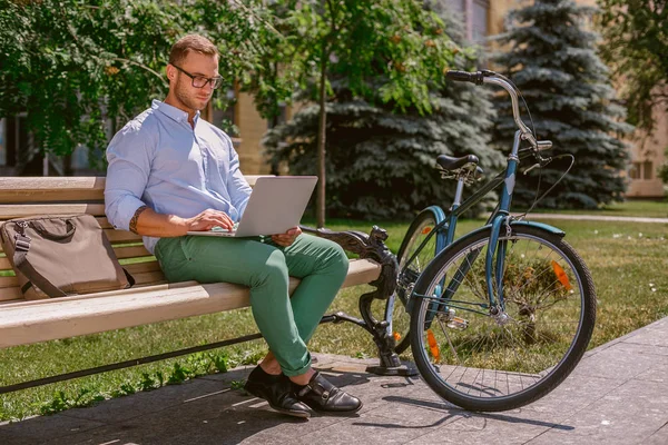 Închiderea mâinilor omului de afaceri tastând pe laptop în timp ce cafeaua se sparge în parc — Fotografie, imagine de stoc