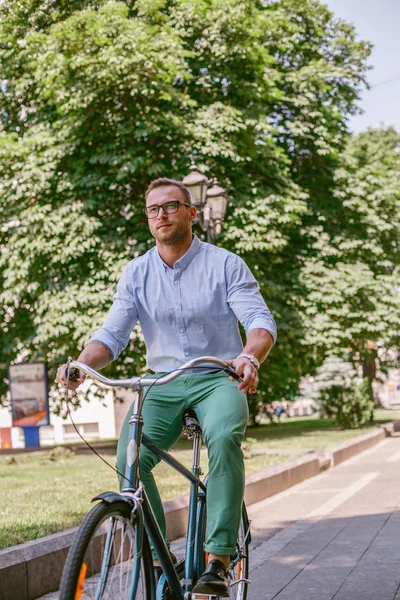 Businessman riding bicycle to work on urban street in morning.