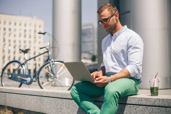 Zajęty szczęśliwym człowiekiem pracy na laptopie poza siedzibą firmy. — Zdjęcie stockowe