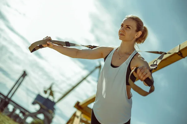 Молода приваблива жінка проводить тренування підвіски з фітнес-ремінцями — стокове фото