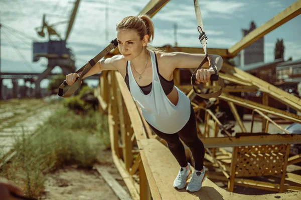 Жінка робить вправи верхнього тіла тренувальними руками з використанням ременів підвіски Trx — стокове фото