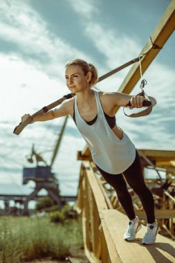 kadının trx süspansiyon kullanarak üst vücut egzersiz eğitim silah yapması