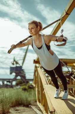 kadının trx süspansiyon kullanarak üst vücut egzersiz eğitim silah yapması