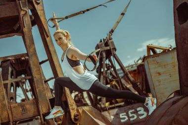 Güzel genç kadının lunges trx ile yapması yan görünüm şeritler