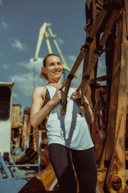 Atletik kadın yapma trx egzersiz bir liman zemin karşı