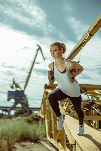 Mujer alegre ejercicio con entrenador de suspensión al aire libre — Foto de Stock