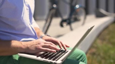 Genç adam şehir sokak üstünde laptop çalışma kulaklık.