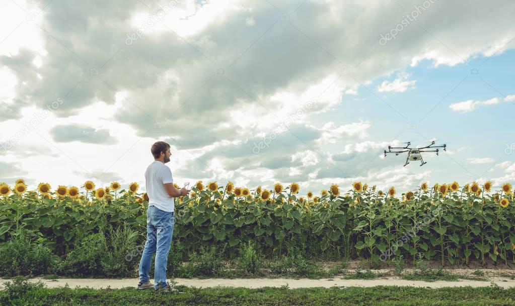 Young man watching and navigating a flying drone in blue clear sky