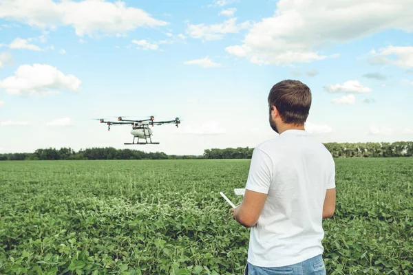 Junger Mann bedient fliegenden Drohnen-Octocopter auf der grünen Wiese. — Stockfoto