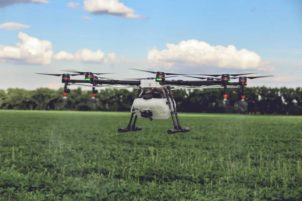 Professionelle große Drohne sprüht Wasser über eine grüne Wiese. — Stockfoto