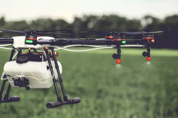Closeup view of agriculture drone spraying water fertilizer on the green field