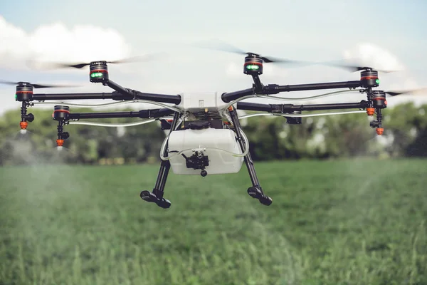 Agriculture drone spraying water or pesticides to grow over green field. — Stock Photo, Image