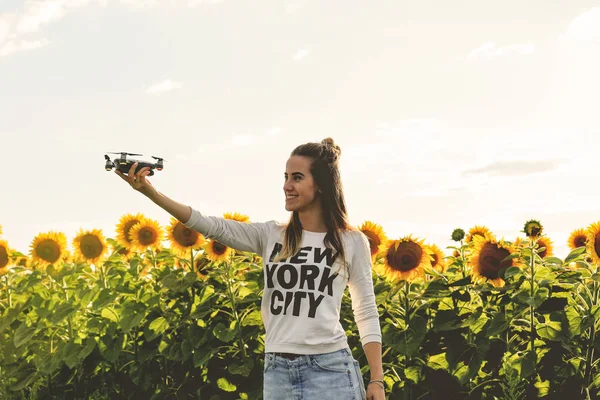 Young woman holding on hand flying mini drone outdoors.