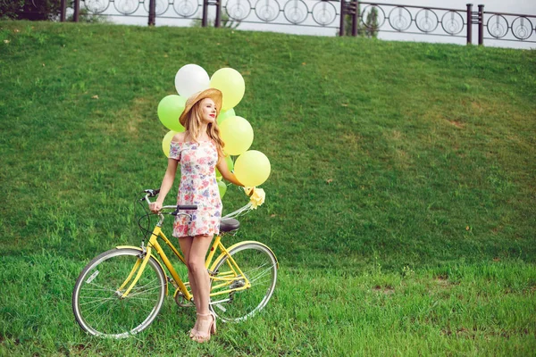 Mulher bonita em uma bicicleta em um fundo de gramado verde . — Fotografia de Stock