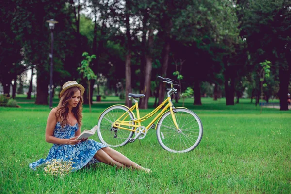 Młoda suczka relaksujący na zielonej trawie z rowerów w parku w słoneczny dzień. — Zdjęcie stockowe